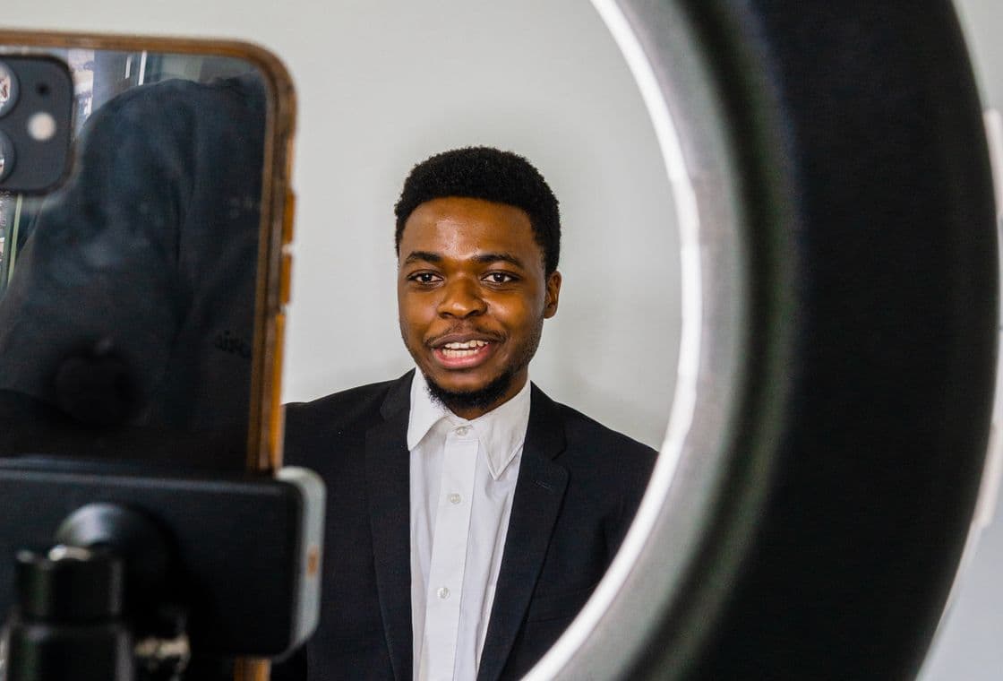A creator recording a video on a phone in front of a ring light